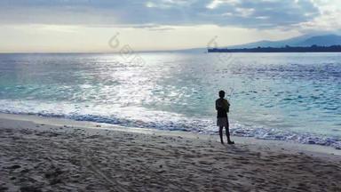 捕捉鱼可爱的少年假期享受生活海滩清洁白色沙子蓝色的背景